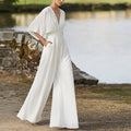 White sleeveless deep V jumpsuit with wide-leg trousers and waist tie
