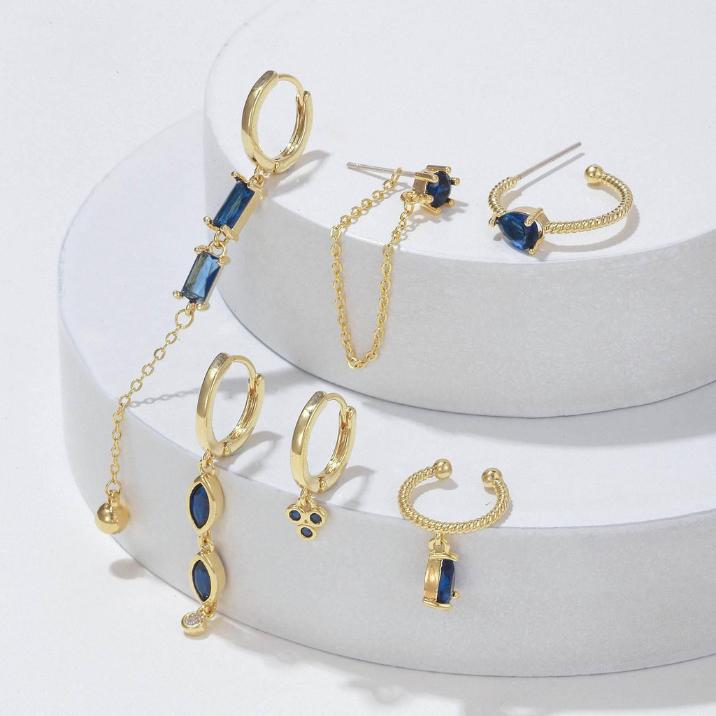 Gold-tone earring set with blue baguette stones, hoops, and dangling chain tassels