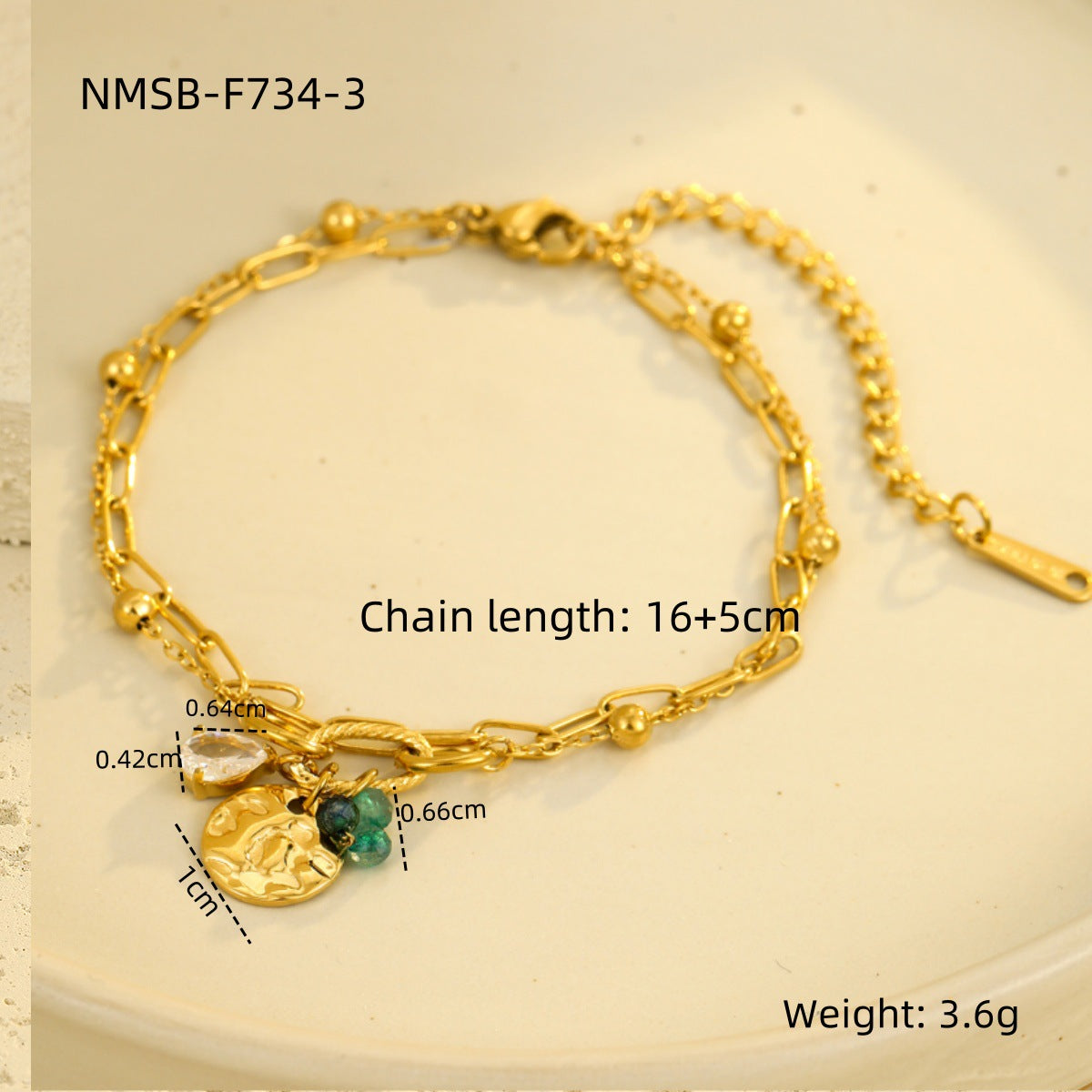 Gold-tone chain bracelet with face medallion charm, green bead, and dangling strand