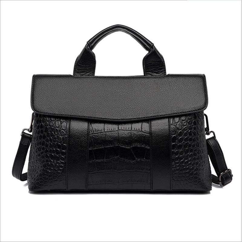 Black embossed handbag with wide top handle, flap front and side shoulder straps