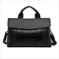 Black embossed handbag with wide top handle, flap front and side shoulder straps
