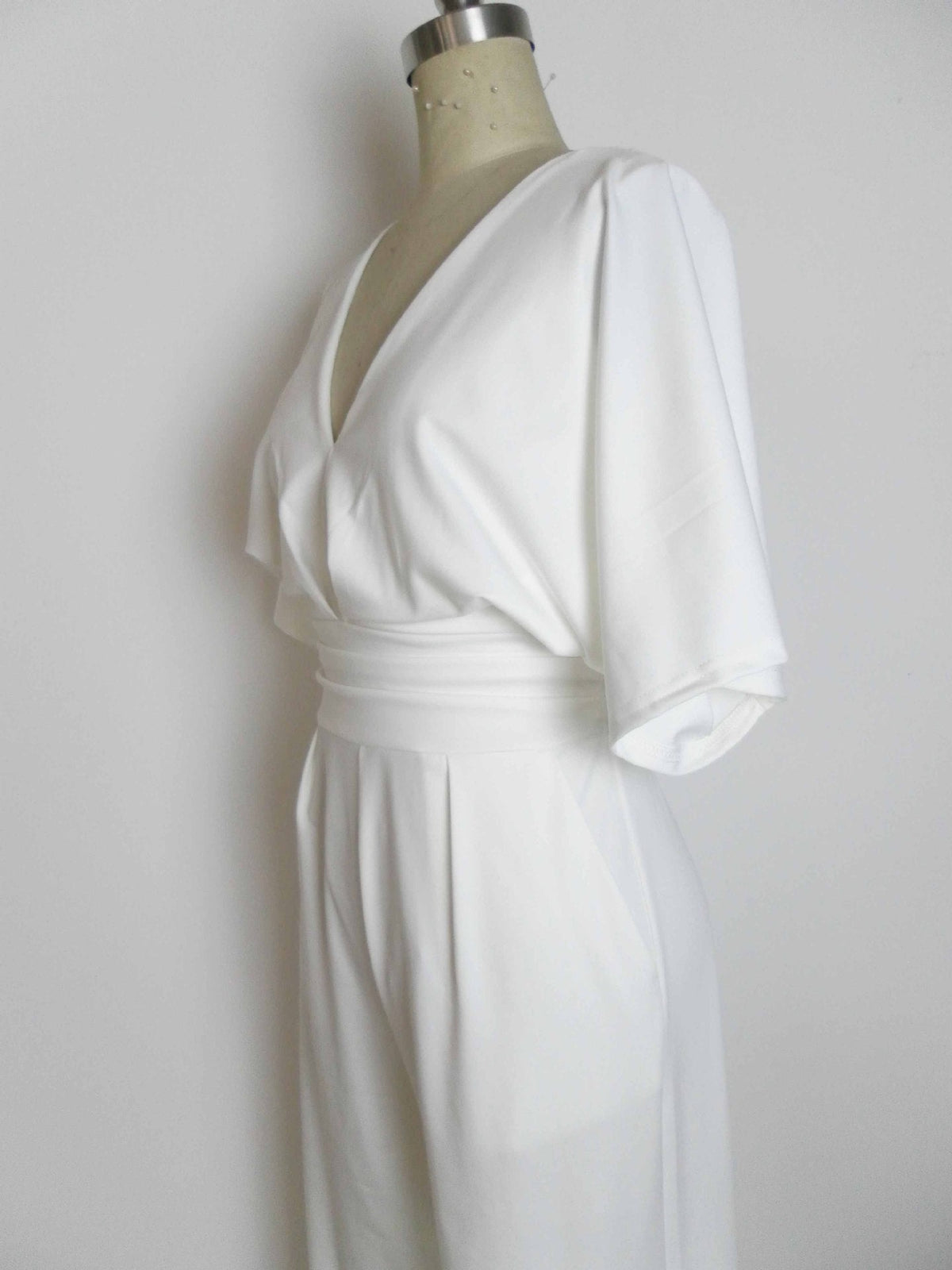 White deep V-neck wide-leg jumpsuit with draped sleeves and belted waist