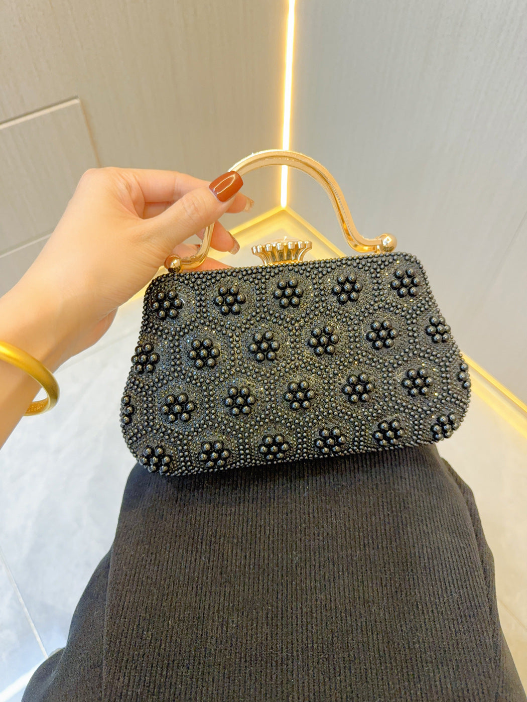 Embellished pearl clutch with top handle, dark fabric, studded round accents