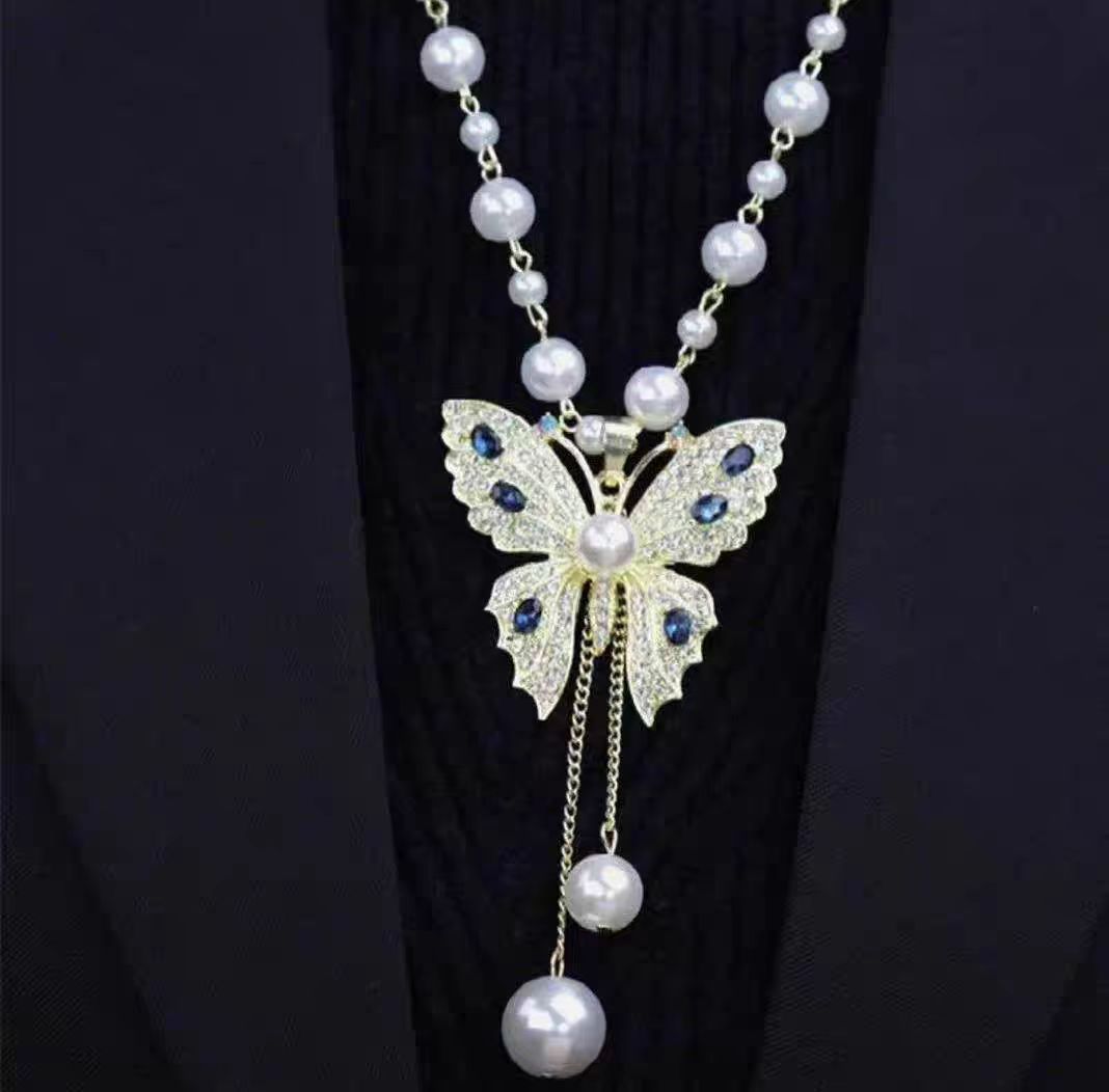 Long pearl beaded necklace with butterfly pendant featuring blue gem accents and pearl drop