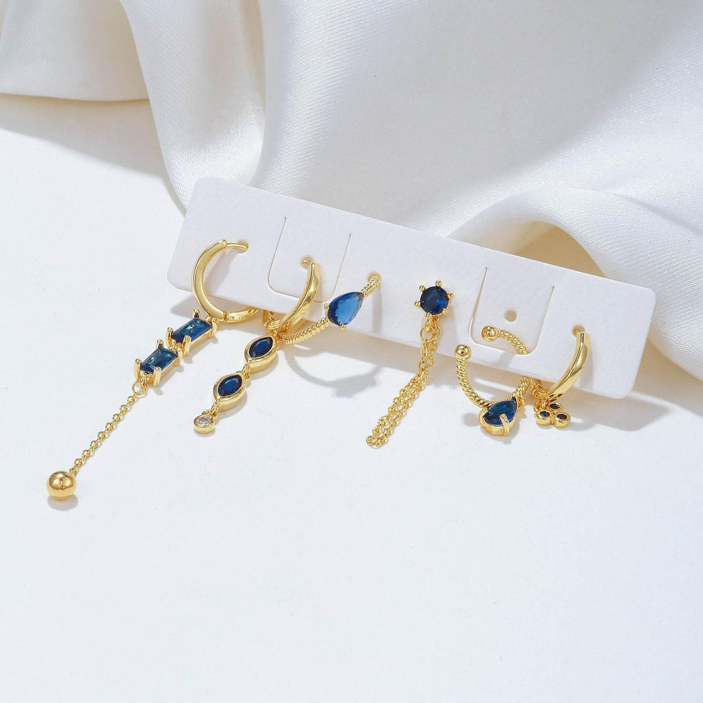 Gold-tone earrings set on card with blue stones, hoops, studs, and chain dangles