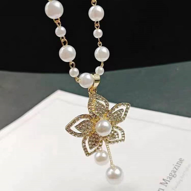 Long pearl necklace with gold flower pendant, white pearl details, and dangling pearls