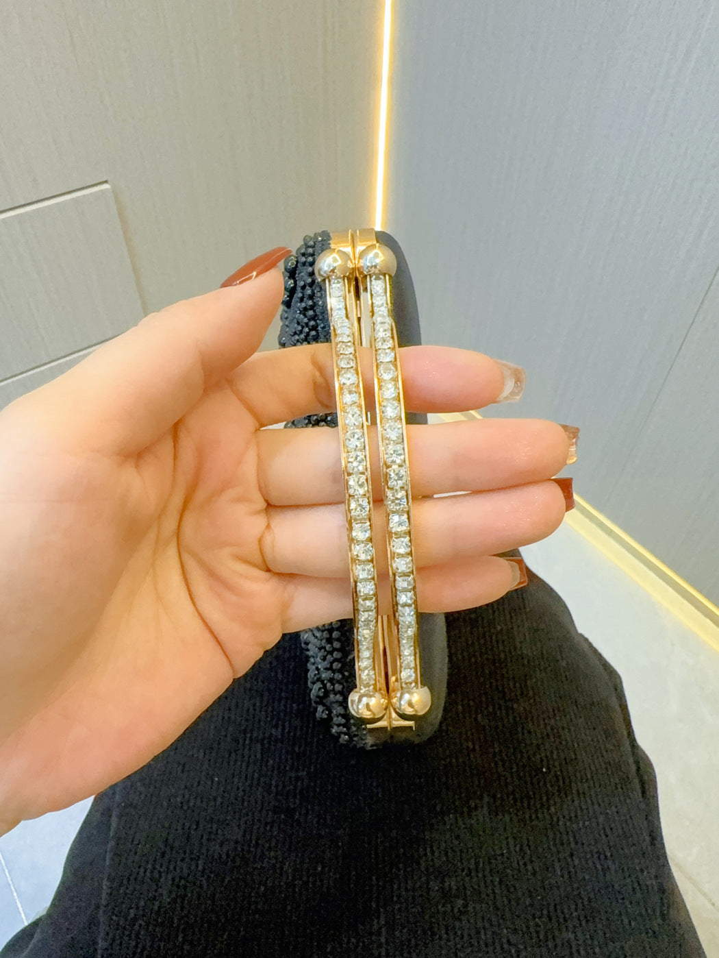 Pearl clutch front strap detail with gold-tone frame and vertical rhinestone trim