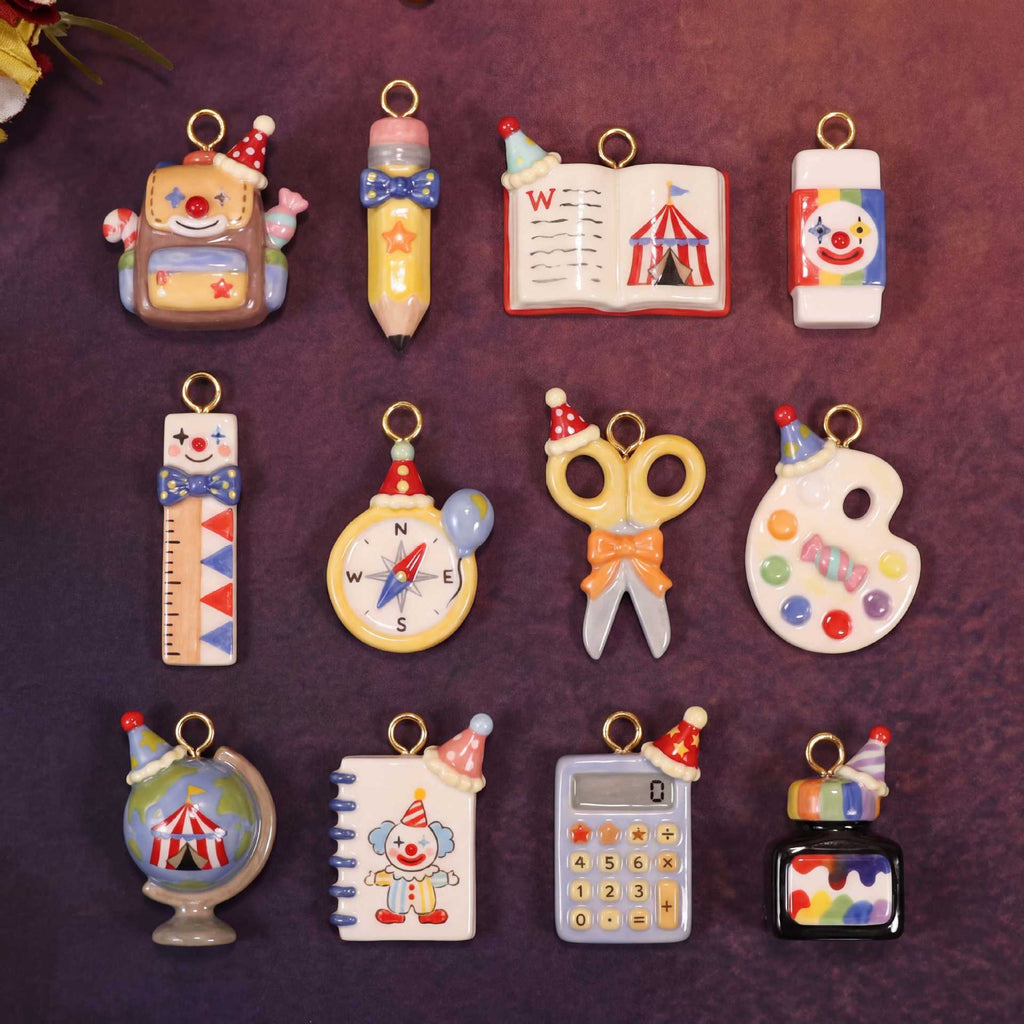 Assorted miniature school-supply keychain charms with gold rings on a dark background