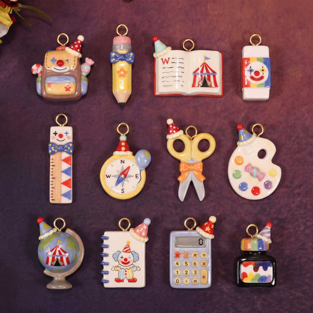 Assorted miniature school-supply keychain charms with gold rings on a dark background