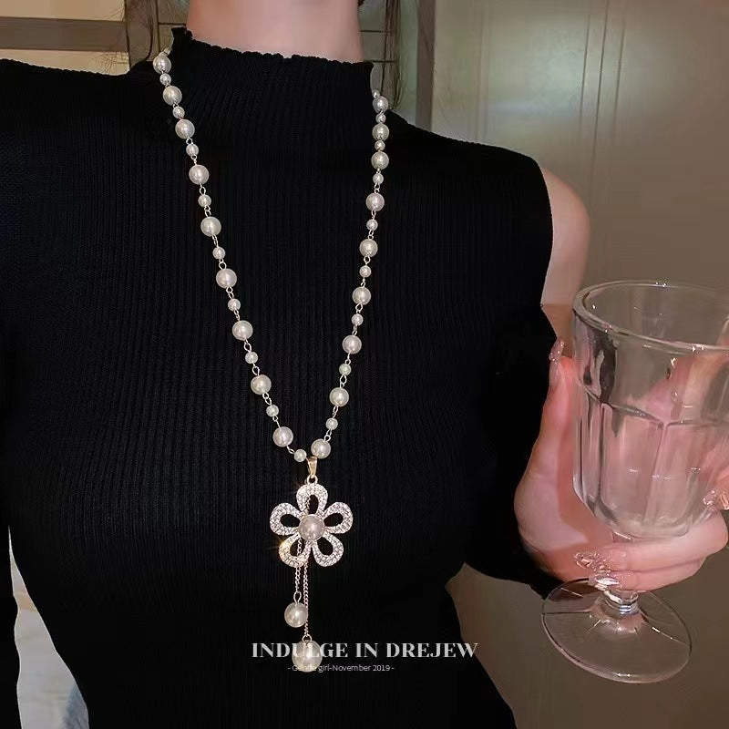 Long pearl necklace with flower-shaped pendant and hanging bead drops
