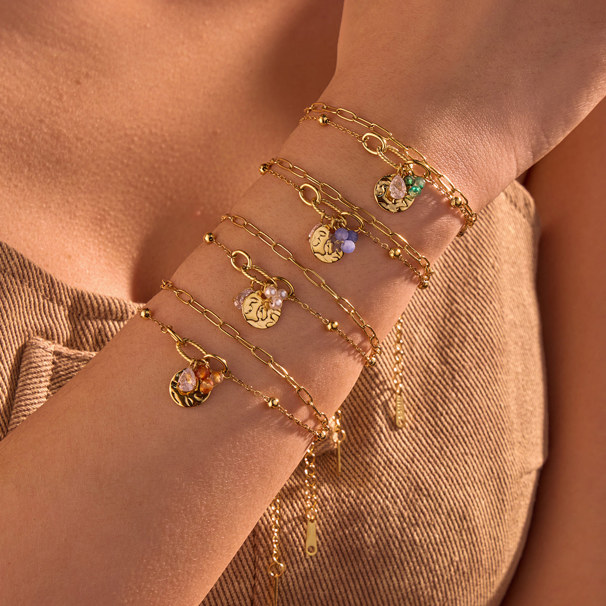 Gold-tone charm bracelet with round zircon accents and dangling beads on wrist