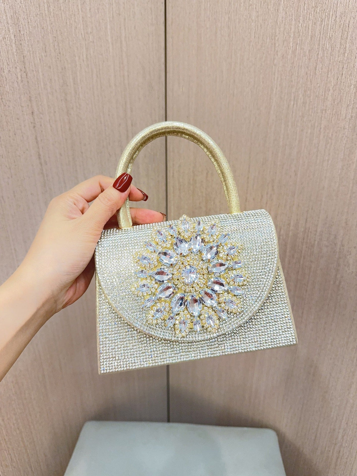 Gold rhinestone flap clutch with ornate crystal medallion front and loop handle