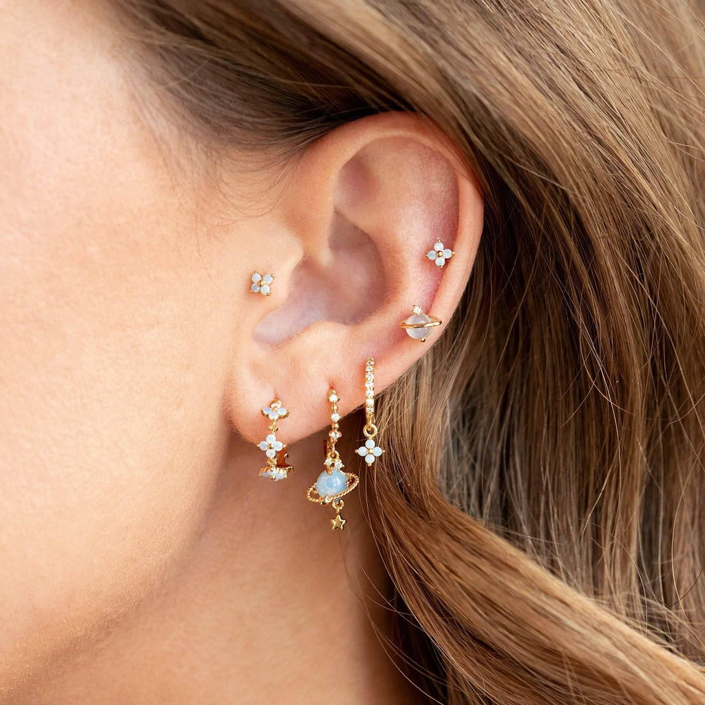 Stackable blue flower and teal drop earrings shown on ear with gold-tone hoops