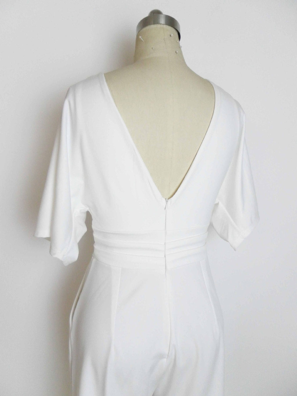 White deep V-neck belted jumpsuit with gathered waist seam and draped sleeves