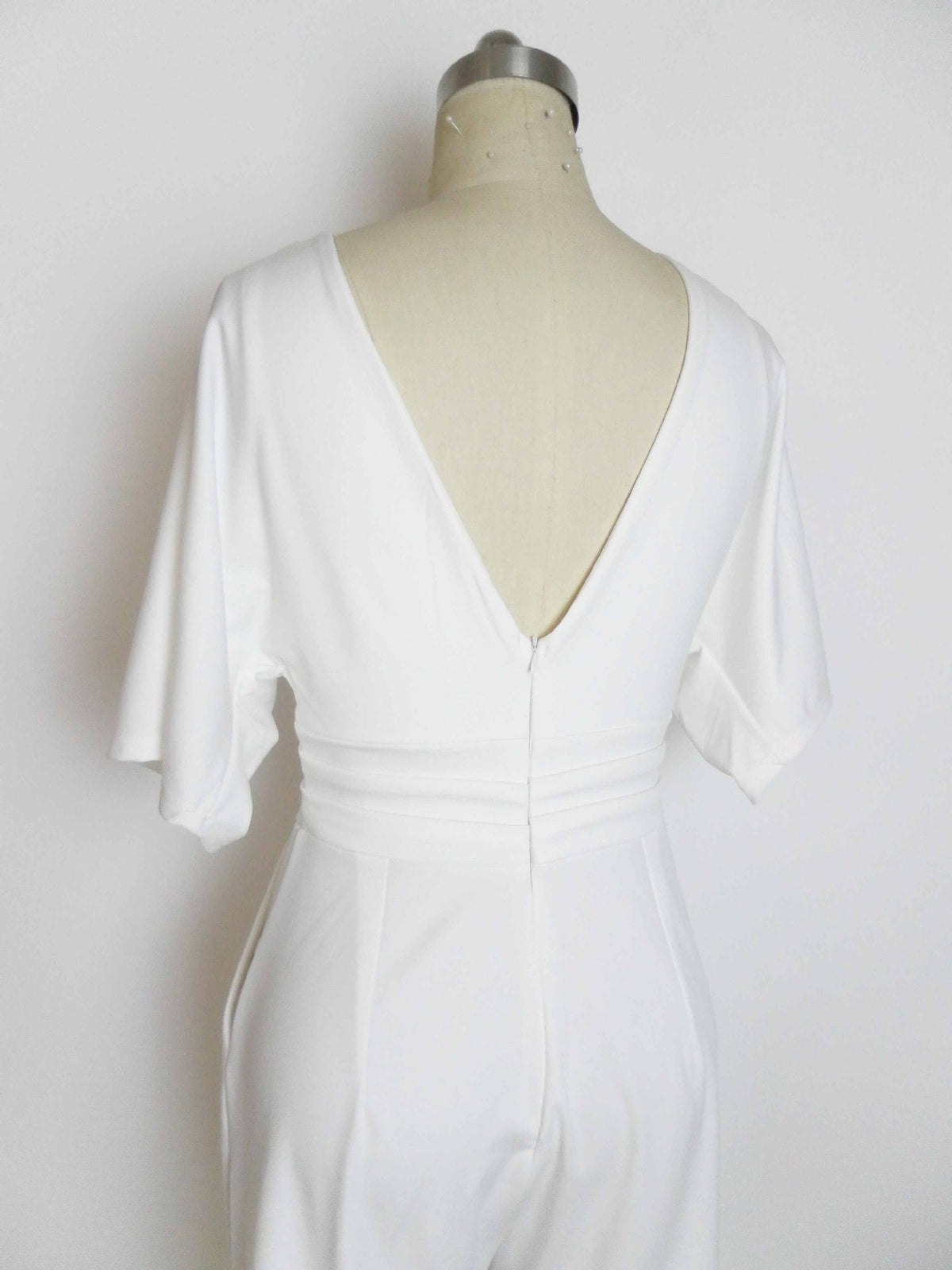 White deep V-neck belted jumpsuit with gathered waist seam and draped sleeves