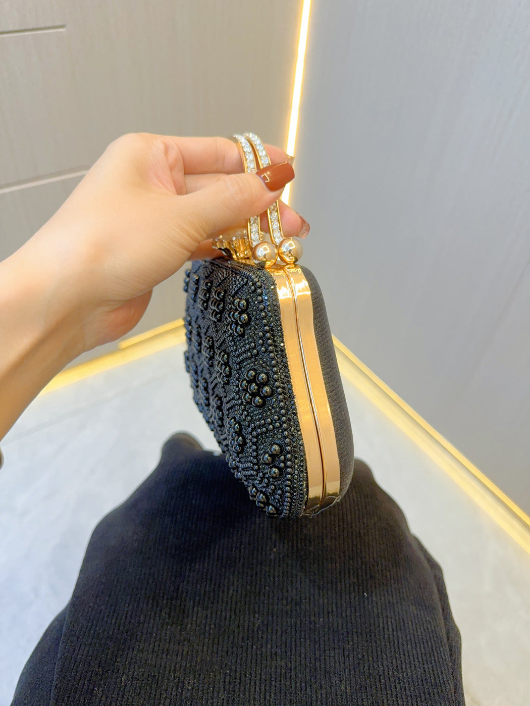 Studded pearl clutch on side view with gold-tone frame and handle