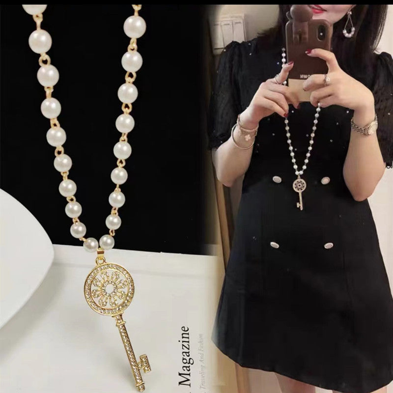 Long pearl necklace with gold key charm and matching chain pearls