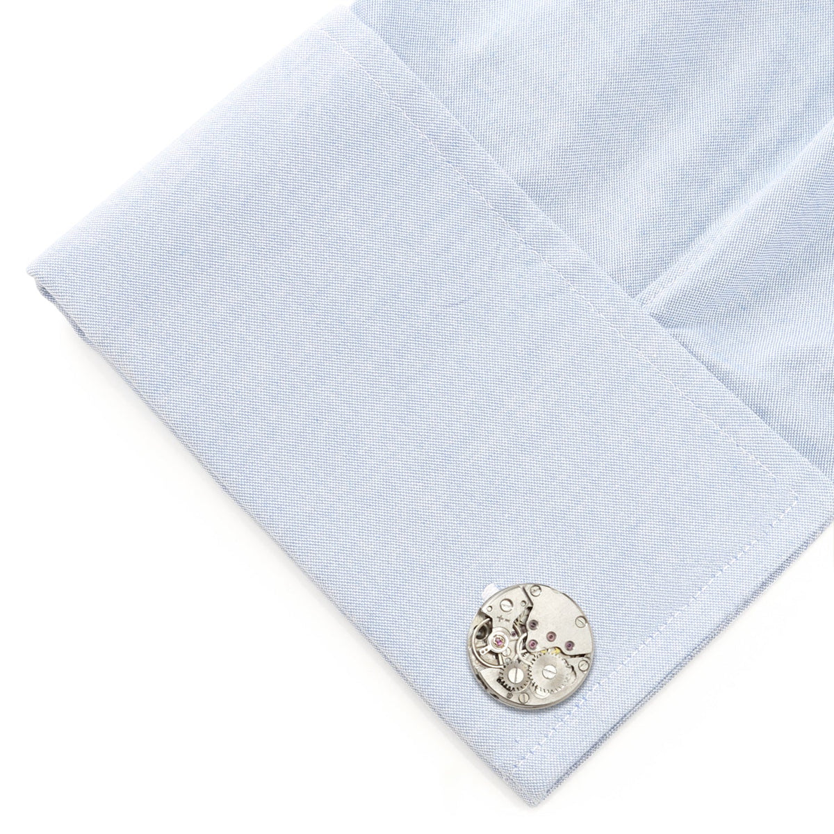 Skeleton watch movement cufflink on light blue fabric cuff, round silver face