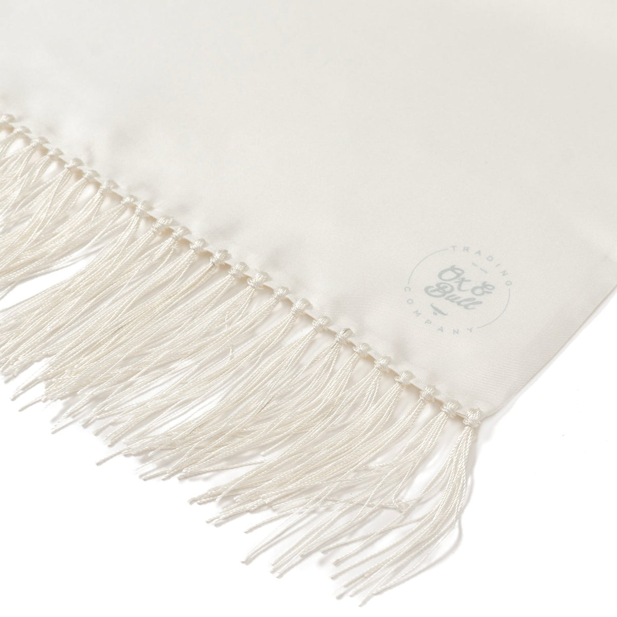 Close-up of white silk scarf fringe with small embossed logo