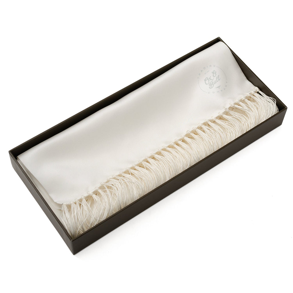 White silk tuxedo scarf laid in a gift box with fringed ends visible