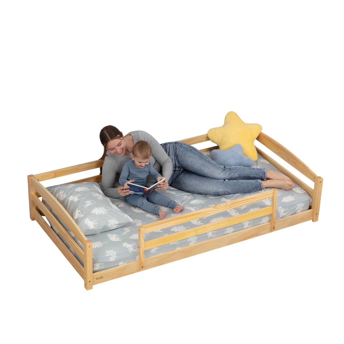 Natural wood twin floor bed with safety guardrails and star pillow on patterned bedding