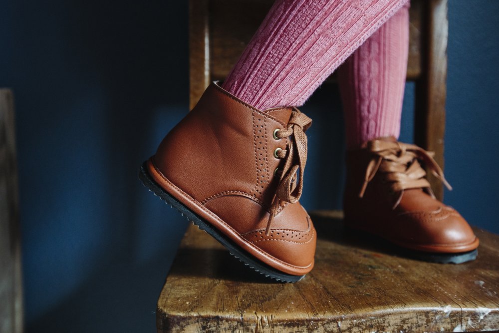 Brown toddler lace-up boots with textured sole on wooden surface