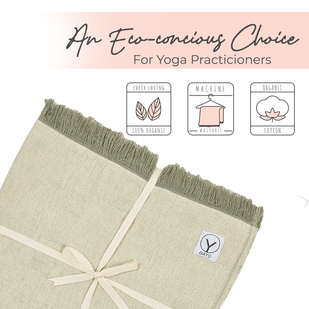 Light green yoga blanket close-up with teal tassel fringe and corner logo patch.