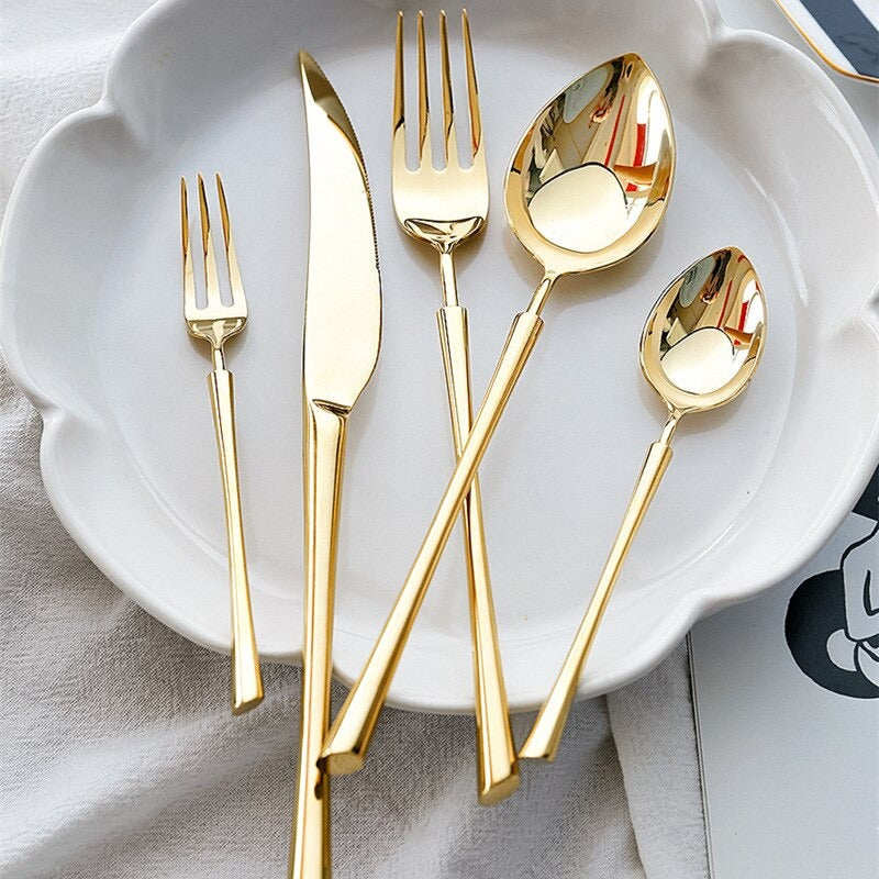 Gold cutlery set on a white plate: forks, spoon, and knife