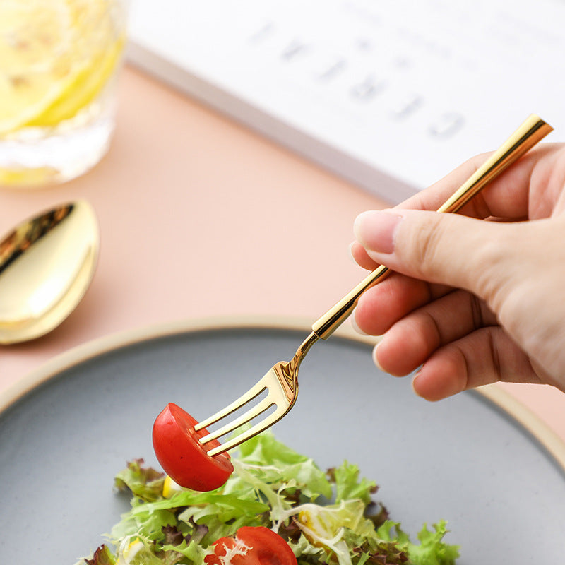 Gold fork held above salad with tomatoes and greens