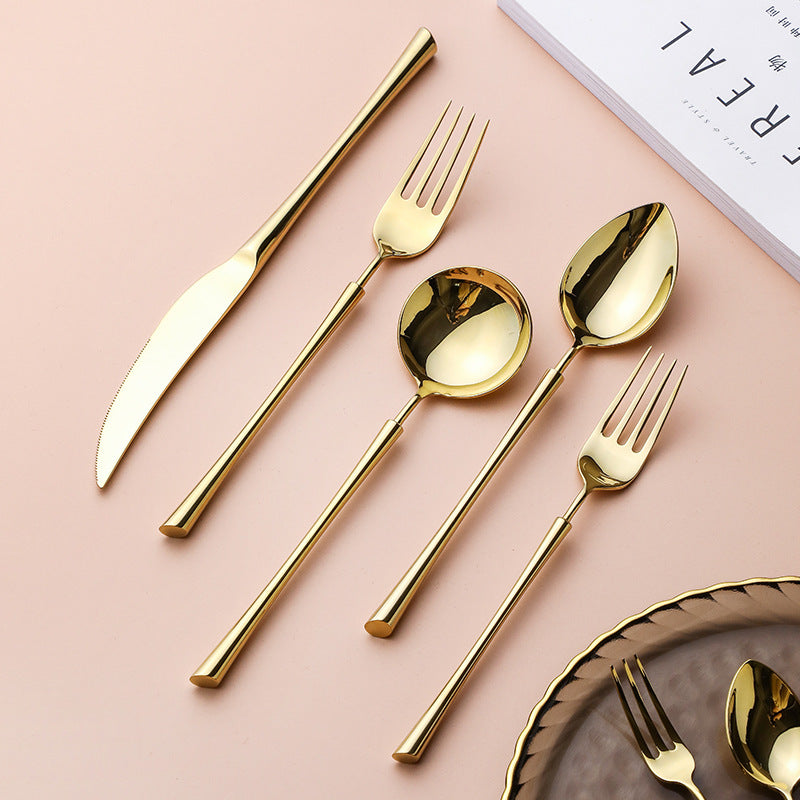 Gold cutlery set laid out: knife, forks, and spoons with mirror finish