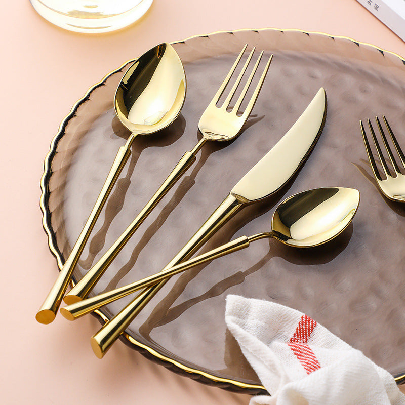 Gold cutlery set with spoon, fork, knife, and small serving pieces on a plate