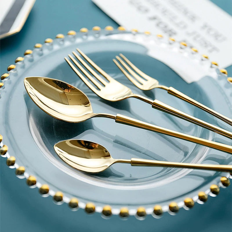 Gold cutlery set on a blue plate: spoons and forks with reflective handles