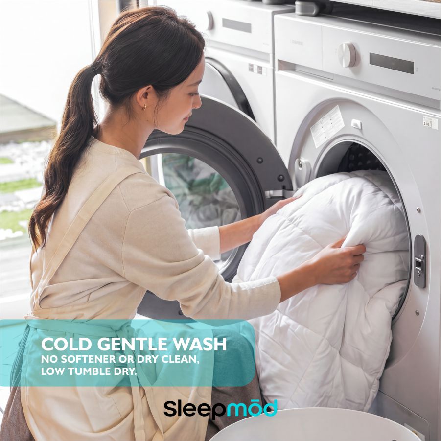 White comforter being loaded into a washing machine