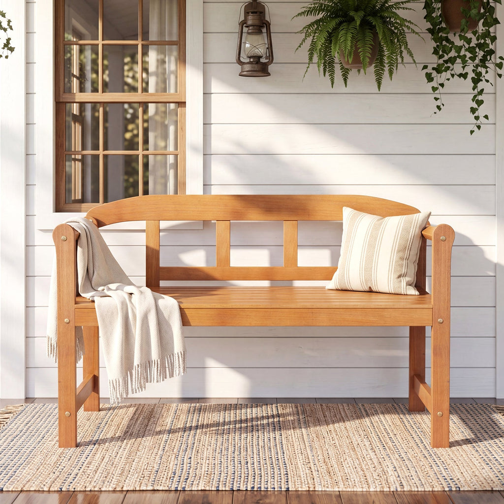 Acacia wood garden bench with backrest and armrests, slatted seat with cushion and throw.