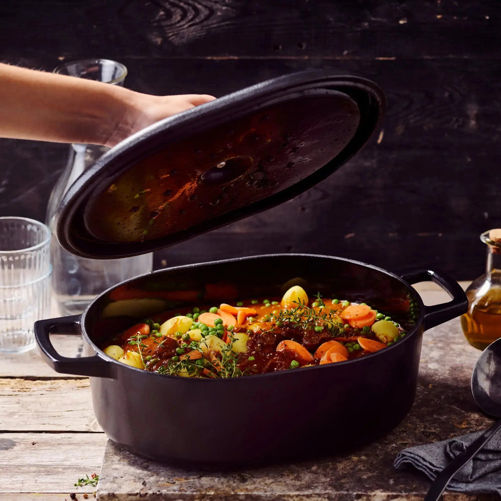 6-qt oval enameled Dutch oven with lid set aside, dark blue enamel and handles