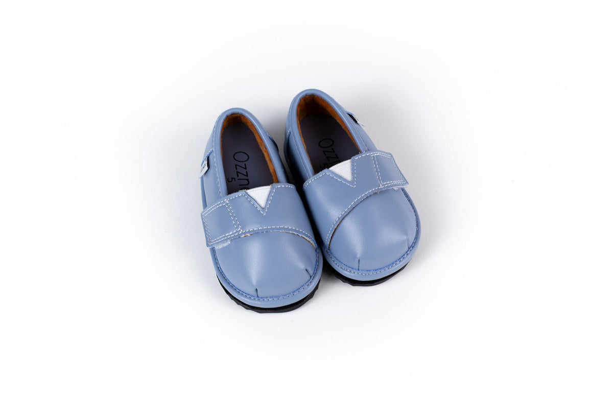 Light blue slip-on barefoot shoes with cross-strap detailing and dark outsole edge
