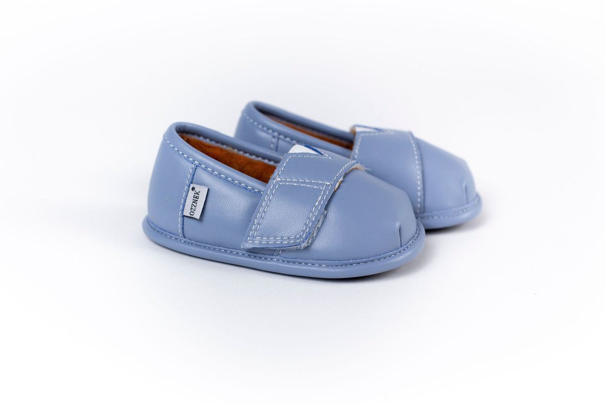 Light blue slip-on barefoot shoes, side profile with strap detail and visible stitching