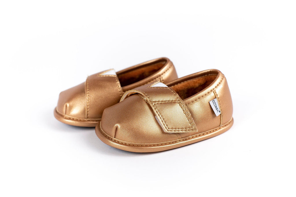 Gold metallic slip-on shoe topper close-up with adjustable strap and stitching