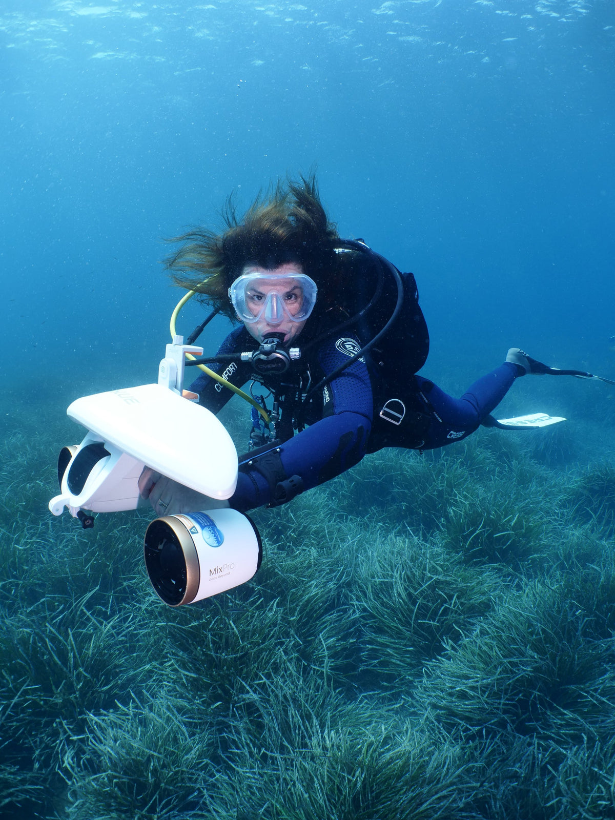 Diver holding an underwater camera device, wearing a mask and regulator