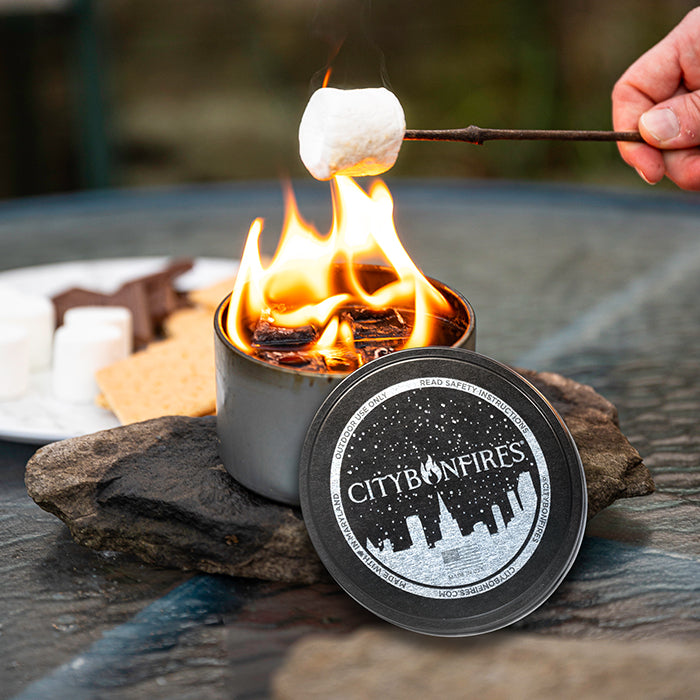 Portable s'mores fire pot with flames and a marshmallow on a stick