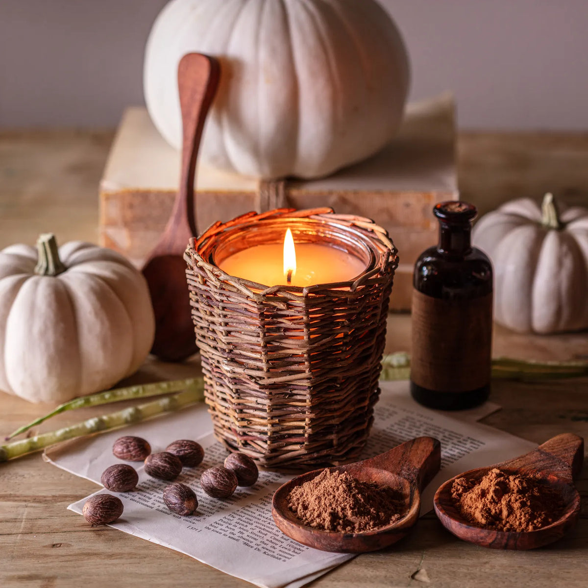 Vintage pumpkin candle: lit wick in woven wicker holder with pumpkin decor