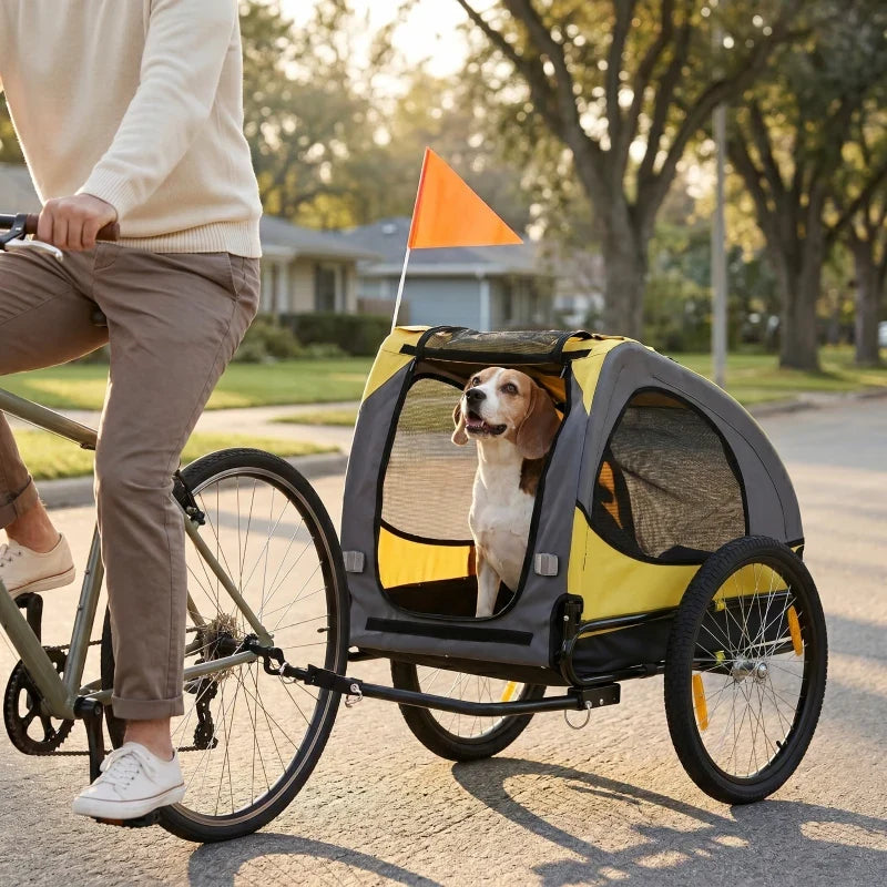 Yellow dog bike trailer pet stroller behind bicycle, with mesh windows and orange flag