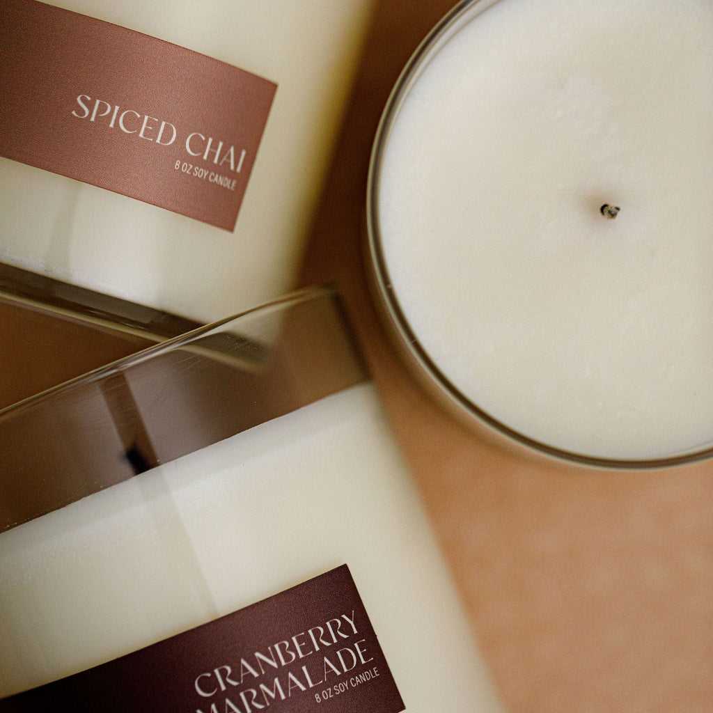 Soy candle jar close-up with white wax and brown label, clear glass rim