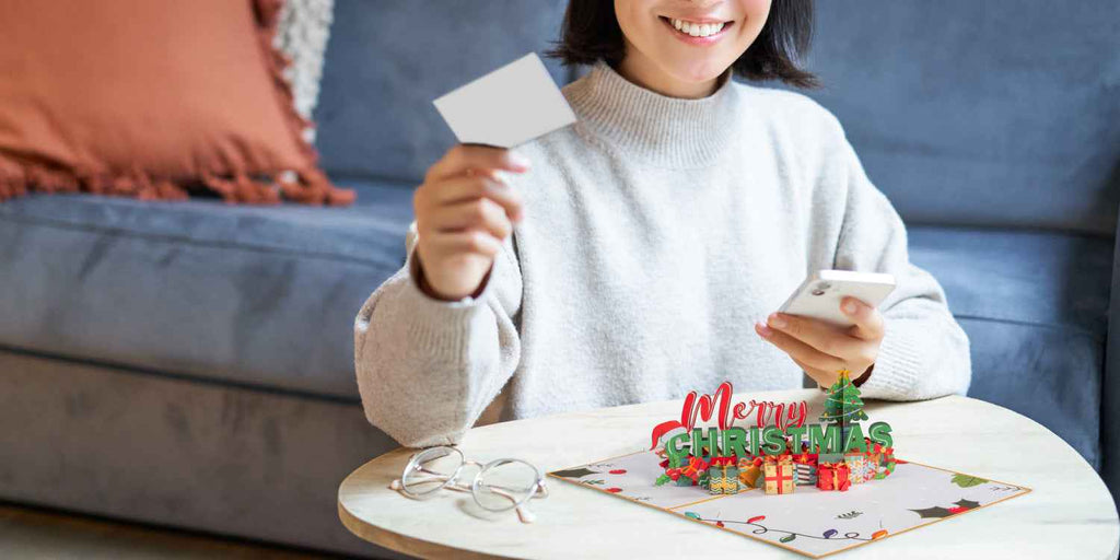 Child holding a Merry Christmas pop-up card with 3D tree and wrapped gifts