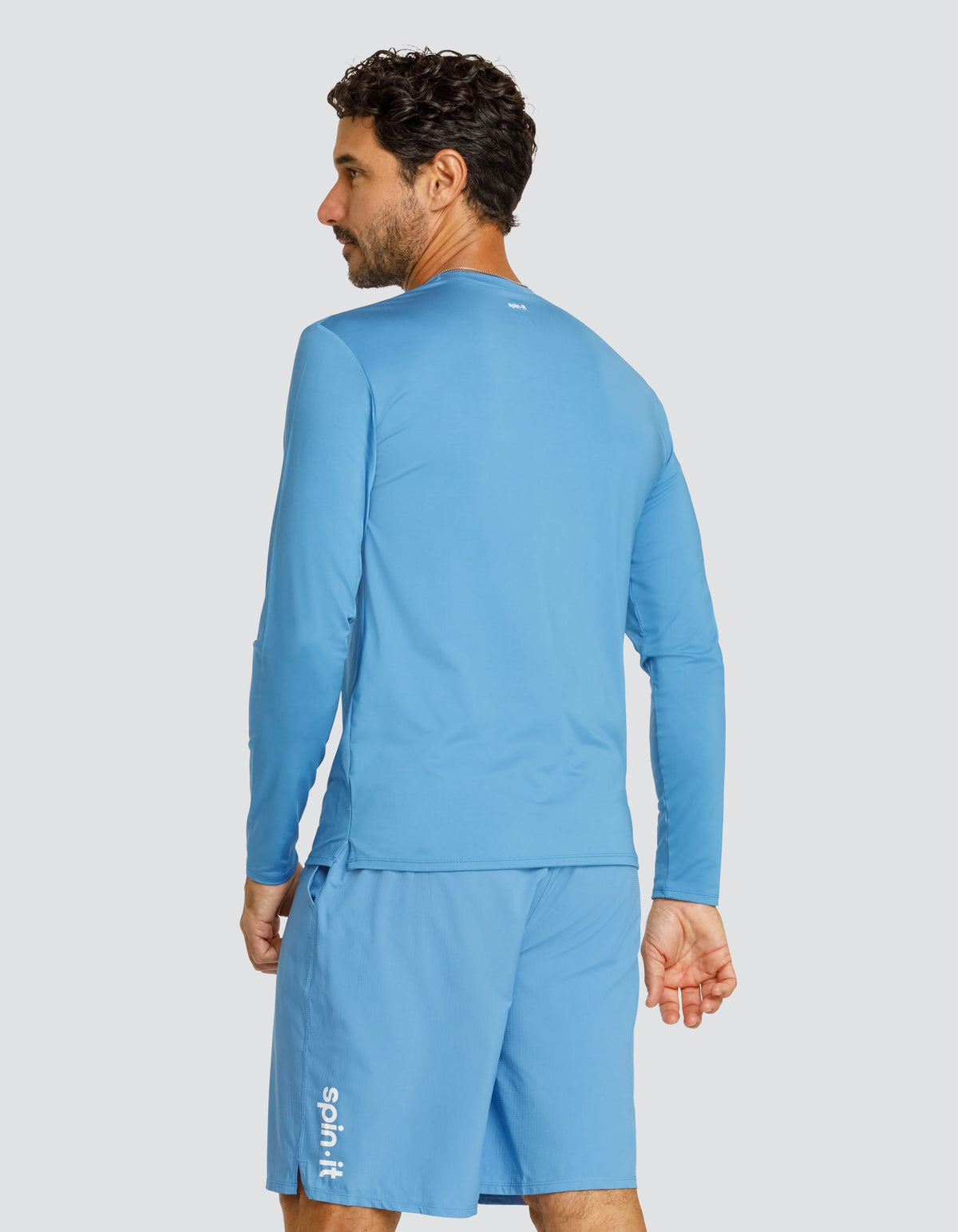 Blue long-sleeve crewneck top, back view with curved hem