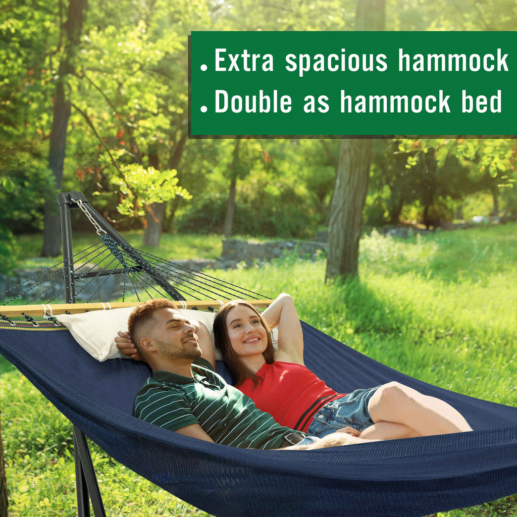 Dark blue double hammock with stand and attached beige pillow, set up outdoors