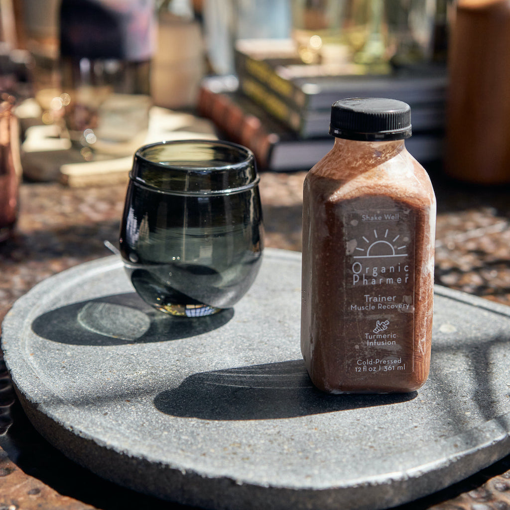 Organic Pharmer Trainer protein shake bottle beside dark glass bowl on tray