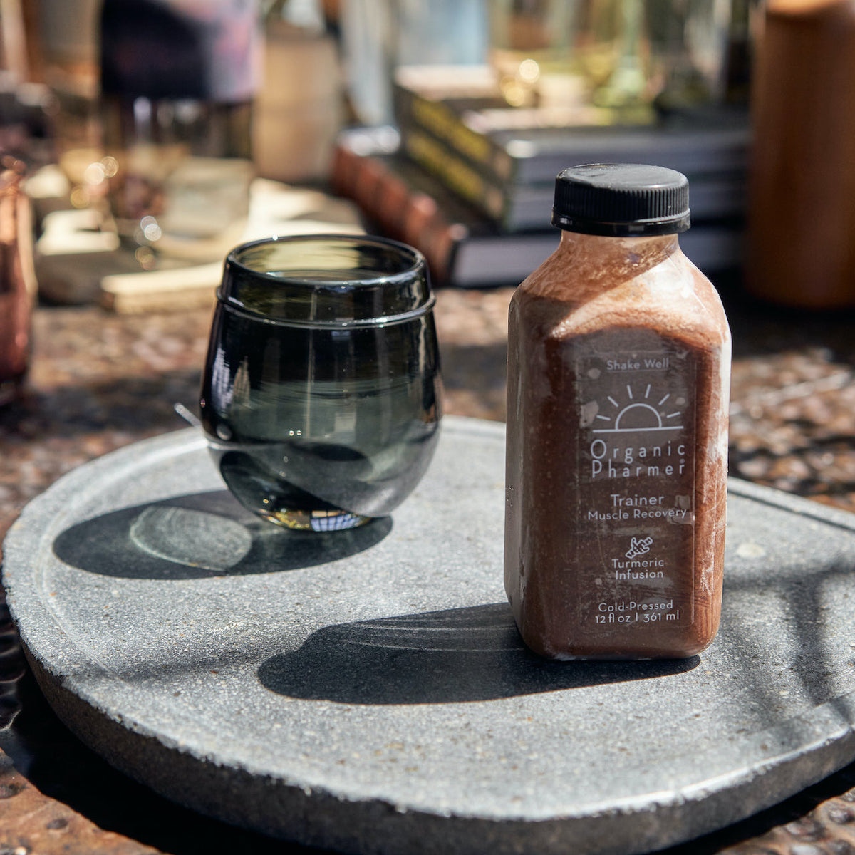 Organic Pharmer Trainer protein shake bottle beside dark glass bowl on tray