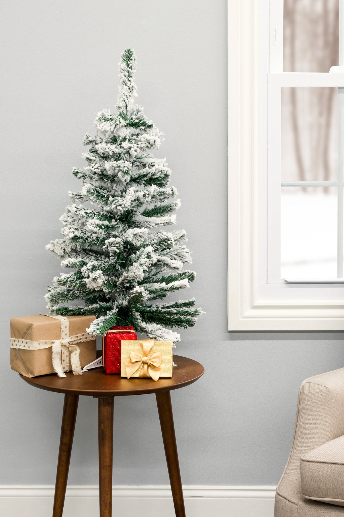Snow-frosted tabletop tree on stand with white flocked branches and layered tips