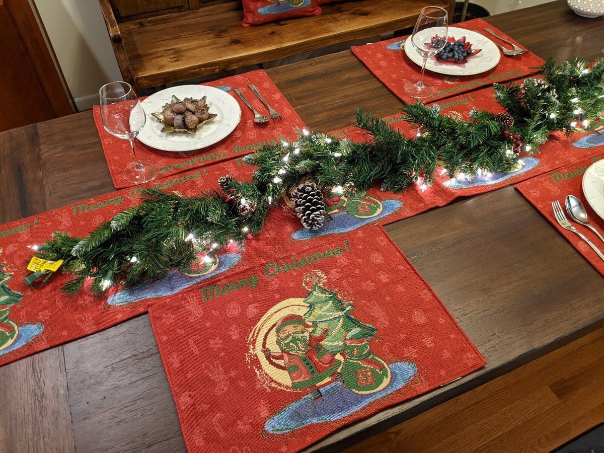 Red Christmas tapestry placemats on dining table with Santa designs and utensils
